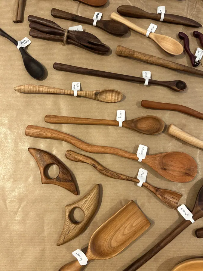 hand-carved wooden scoops and spatulas arranged on a bench